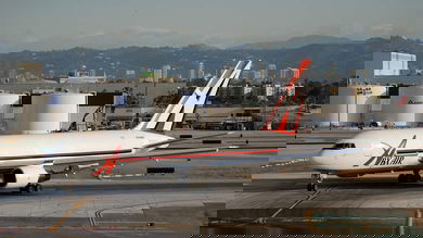 A white ABX Air jet moves down runway with giant fuel tanks in the background.