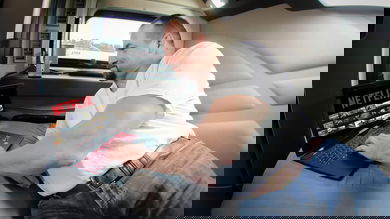 Truck driver in his sleeper selecting a streaming movie to watch.
