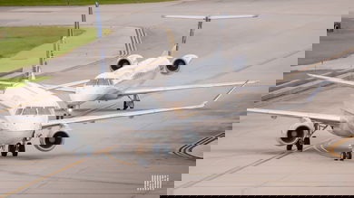 Two small regional jets taxi on airport roadway.