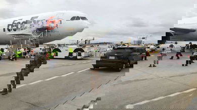 Armed guard on tarmac in front of a FedEx plane getting loaded with COVID vaccine.