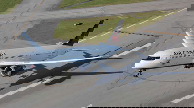 A white jet lifts off the runway. View from above and in front of plane.