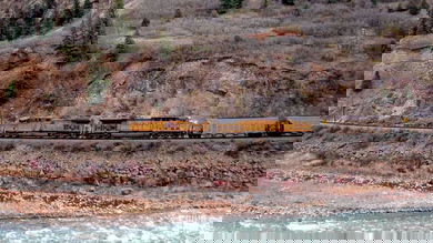 A photograph of a Union Pacific train traveling by a rocky mountainside.