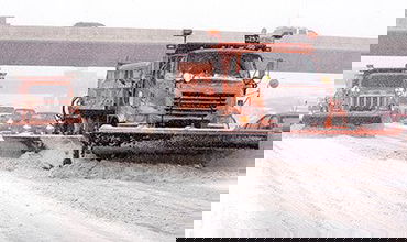 Plow trucks clearing a Minnesota highway, with traffic behind it.