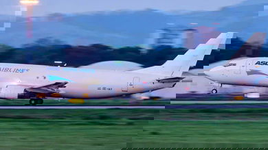 A white cargo jet touches down on runway.