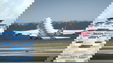 Image of COVID vaccine vials on left, and a large freighter taking off from runway (view from behind)