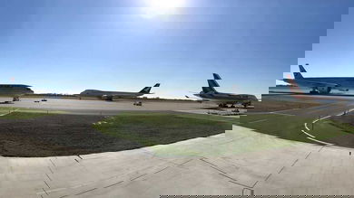 Landscape photo of three planes on tarmac on sunny day