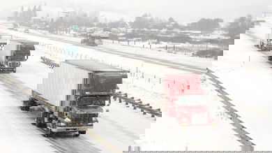 Tractor-trailers heading down snowy highway.