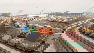 A photograph of a rail yard with parked railcars and intermodal containers.