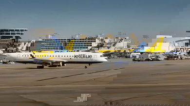 A small white and blue jet on the tarmac with a yellow jet in the background.