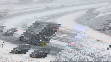 Tractor-trailer and cars heading down Nebraska highway on a snowy day.