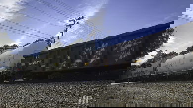 A photograph of rail cars rolling by a railroad crossing.