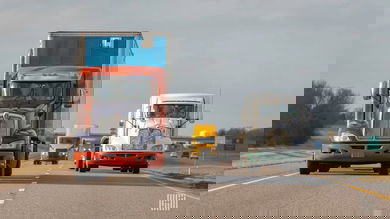 Three semi-trucks travel on a highway, seen from the front at varying distances.