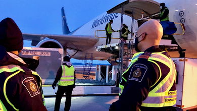 Canada Border Services Agency officers look on as cargo is unloaded from a UPS cargo flight.