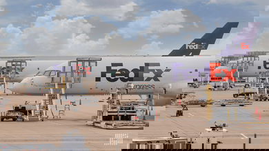 FedEx aircraft on the ground waiting to be loaded on a sunny day.