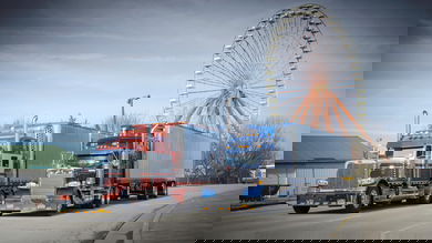 Two Peterbilt trucks with ferris wheel in background