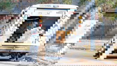 Driver in back of Postal Service vehicle unloading packages