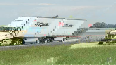 White XPO truck on the highway hauling two trailers