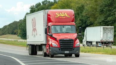 A red Saia tractor and white trailer on the highway