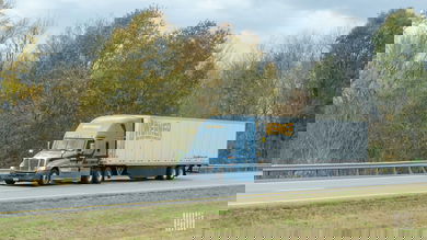 A blue Werner tractor pulling a white Werner trailer on a highway
