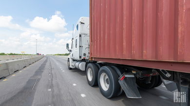 A white tractor pulling an ocean container
