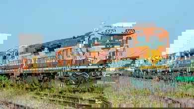 A BNSF train passes travels across a field.