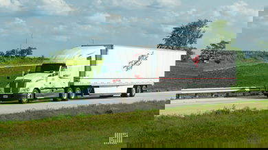 A white Heartland tractor pulling a white Heartland dry van trailer