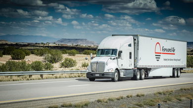A white tractor pulling a Forward Air trailer on the highway