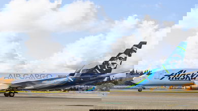 An Alaska Air Cargo jet with blue tail on runway. Side view.