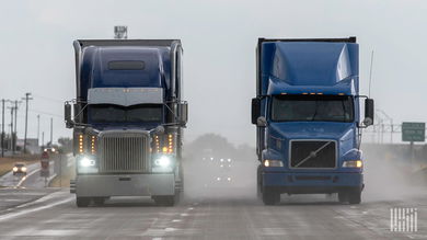 front view of two tractor-trailers on a rain-soaked highway