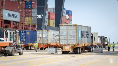 Images shows trucks, containers and container crane.