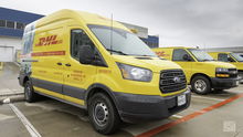 Yellow DHL delivery vans in a parking lot.