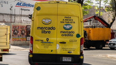 Rear view of a yellow Mercado Libre delivery van on a city street.