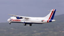 A Purolator cargo plane flies under propeller power at low atltitude.