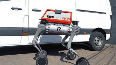 A four-legged robot with wheels is positioned next to a white delivery van.