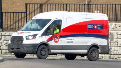 A red-and-white Canada Post van makes deliveries in a suburban neighborhood.