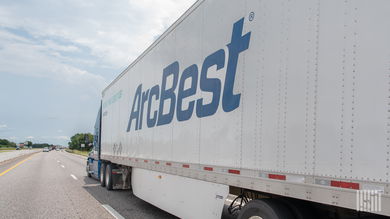 A sideview of an ArcBest trailer being pulled on a highway