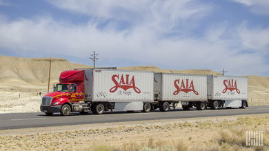 a red Saia tractor pulling three Saia pup trailers in a desert