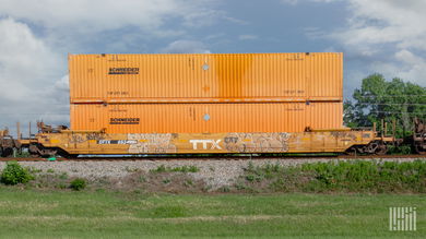 Two orange Schneider intermodal containers doubled stacked on a well car