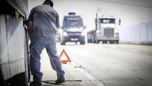 Truck driver on highway fixing his truck