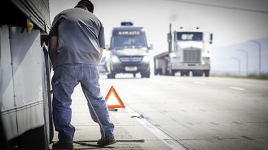 Truck driver on highway fixing his truck