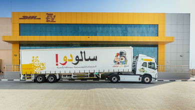 A truck with Arabic brand name is parked in front of a DHL warehouse in Saudi Arabia.
