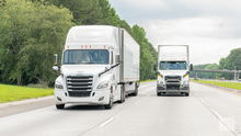 Two white tractor-trailers on a highway