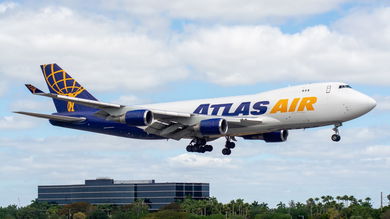A blue-tailed Atlas Air jumbo cargo jet with gold lettering comes in for a landing.