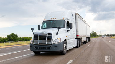 A white sleeper cab pulling two white LTL pup trailers